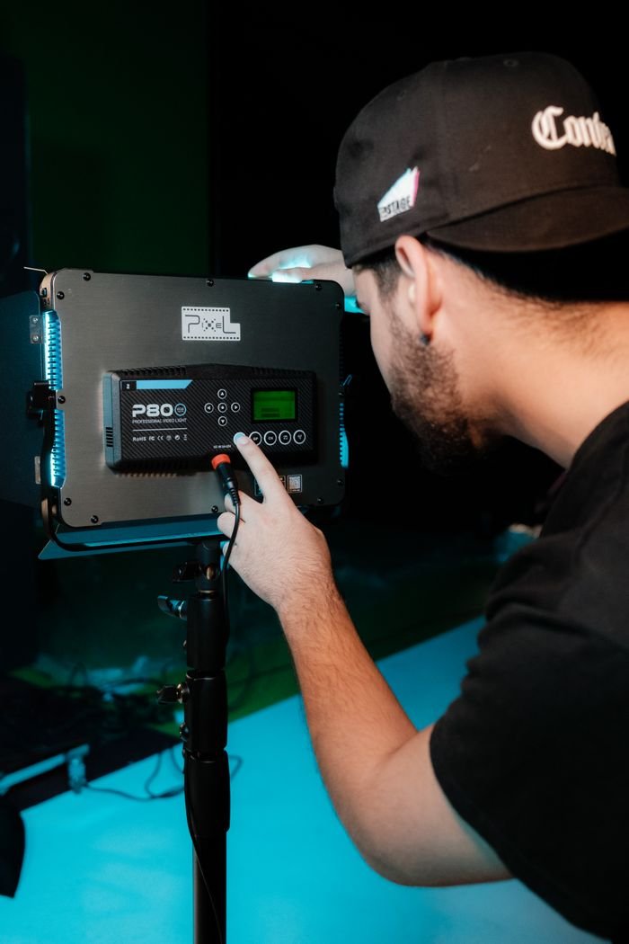 Photographer adjusting studio video light for optimal shoot lighting.